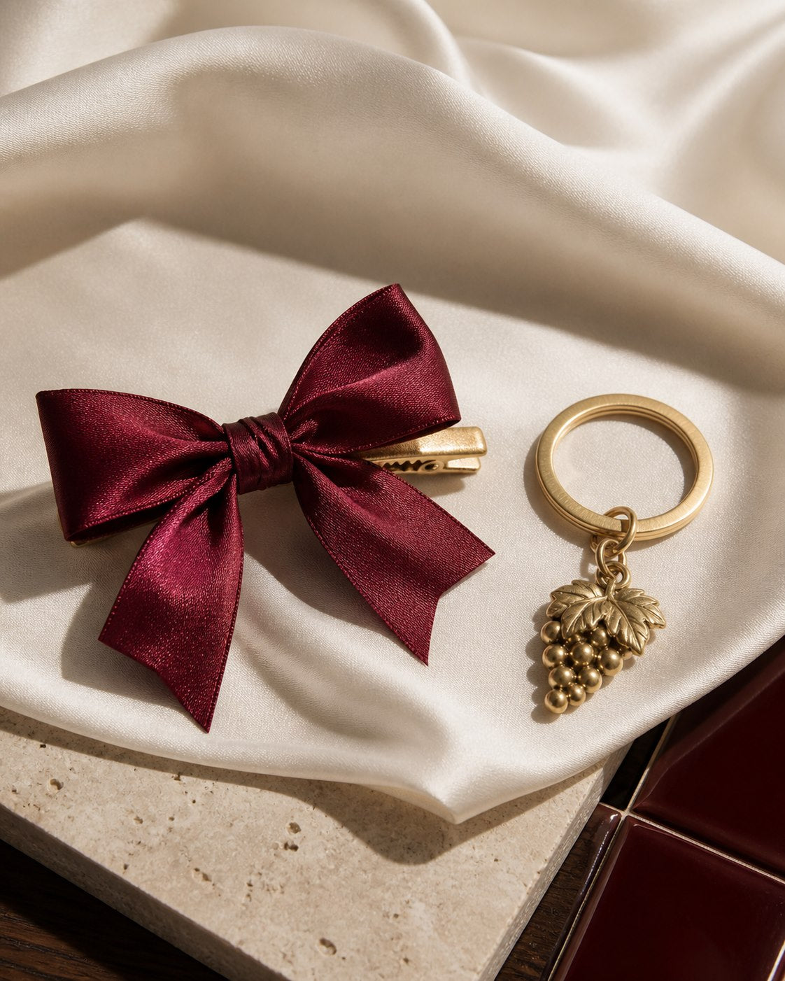 Editorial still life of a cabernet satin bow and gold grape keychain