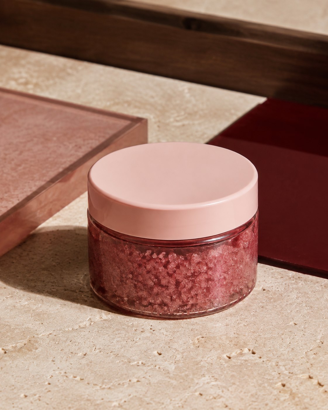 Editorial still life of a berry-pink sugar scrub jar